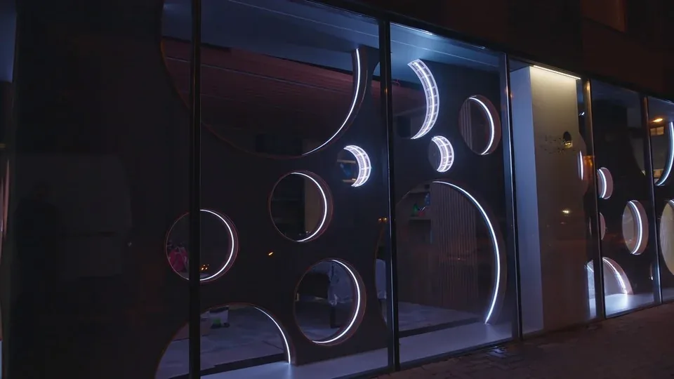 Coin-shaped openings in a showroom facade lit with addressable pixel LED rings