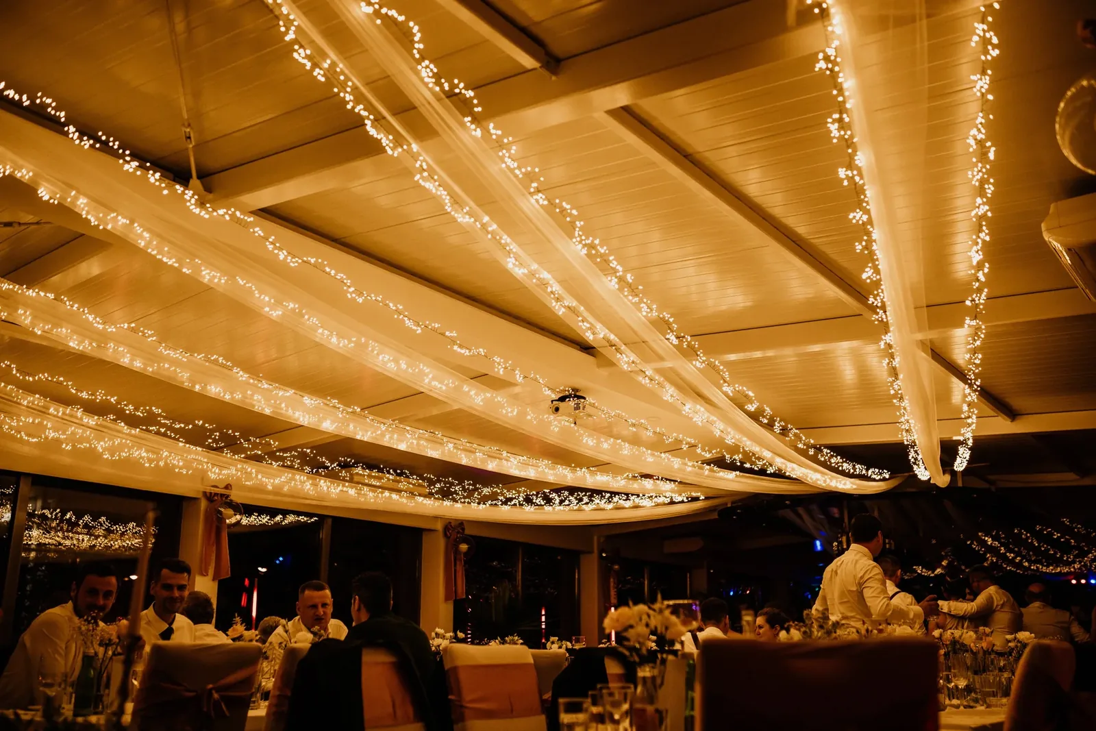 Wedding venue ceiling with fabric drapes and dimmable warm white string lights