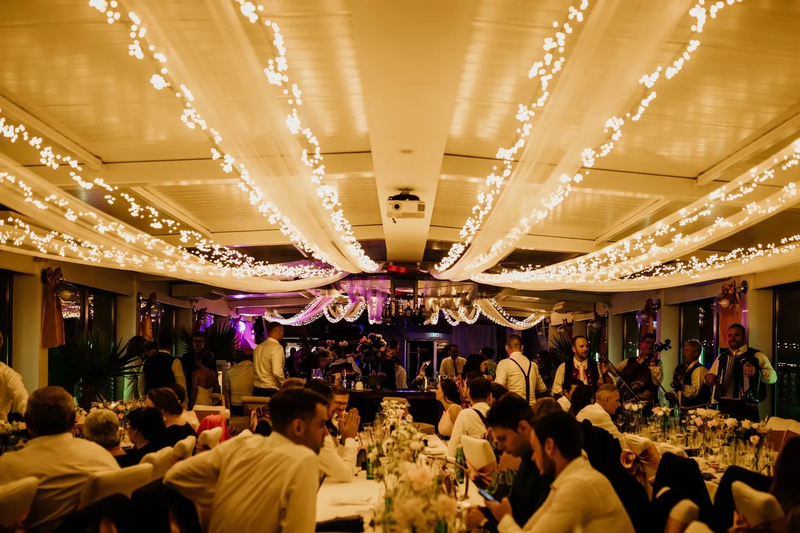 Wedding dinner under dimmable festoon lights and Edison bulbs in warm white