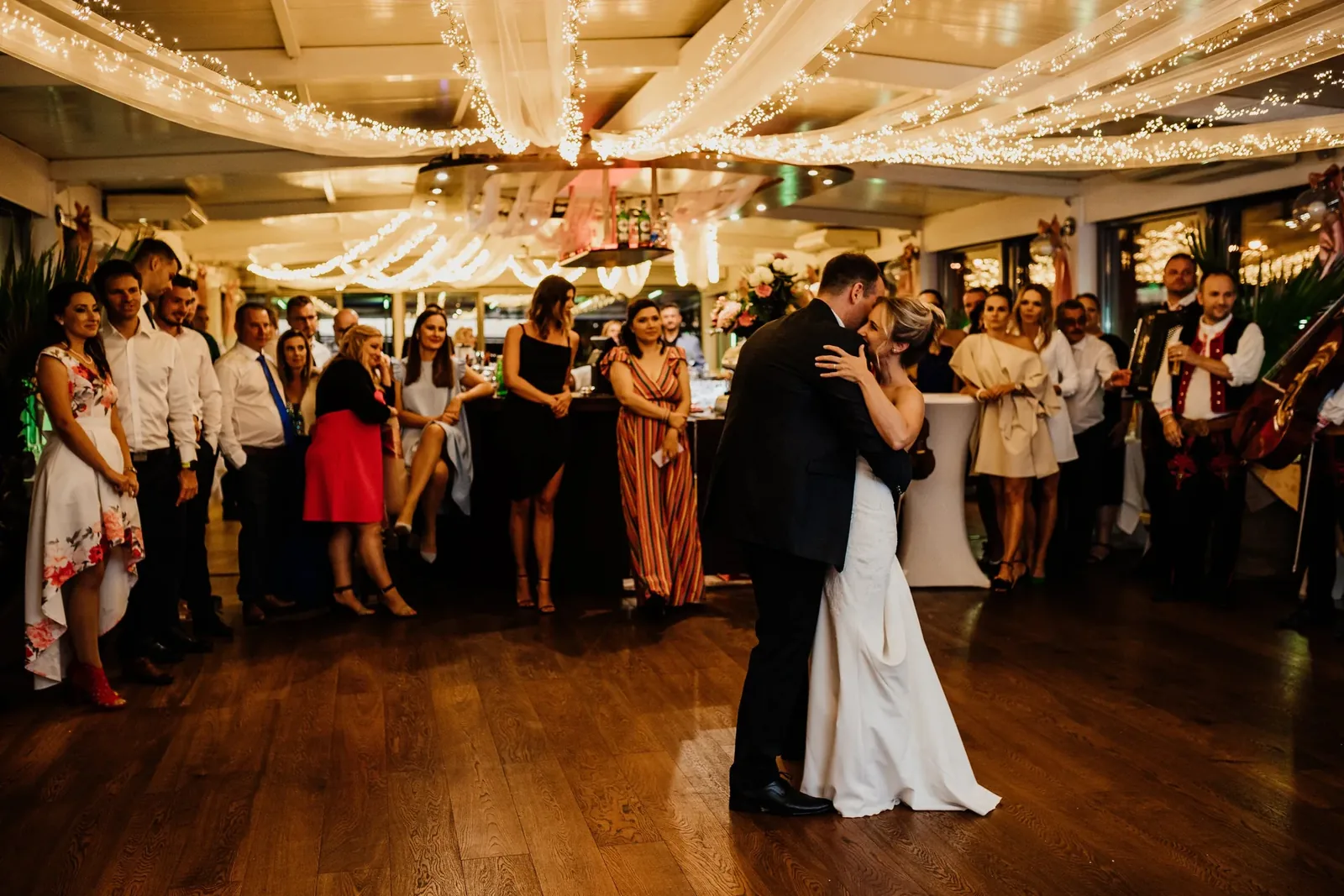 Bride and groom dancing under dimmed warm white wedding lighting