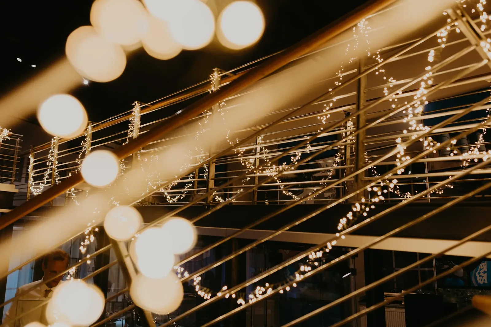Warm white Edison bulbs and festoon lights along railings at a wedding venue