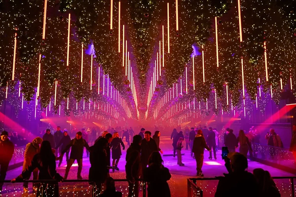Ice rink under hanging Christmas trees in purple and orange light