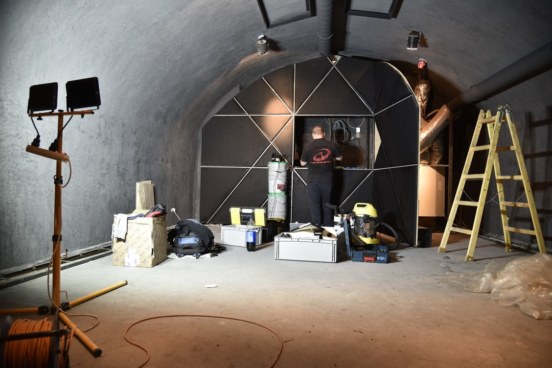 One man is wiring together different parts of a wall installation that creates a simpe patter using LED strips.