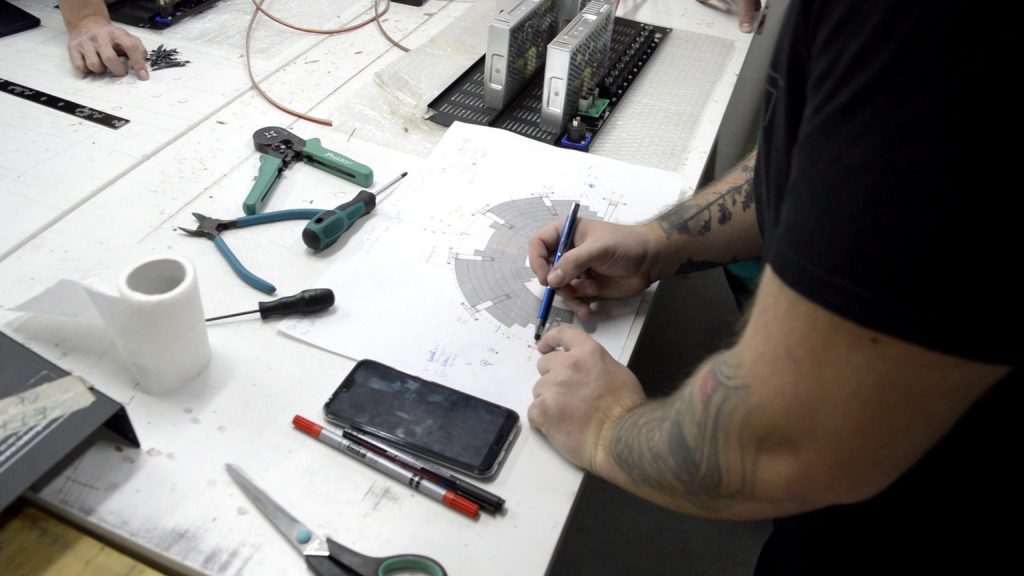 Technician at our workshop with blueprint of installation on table.
